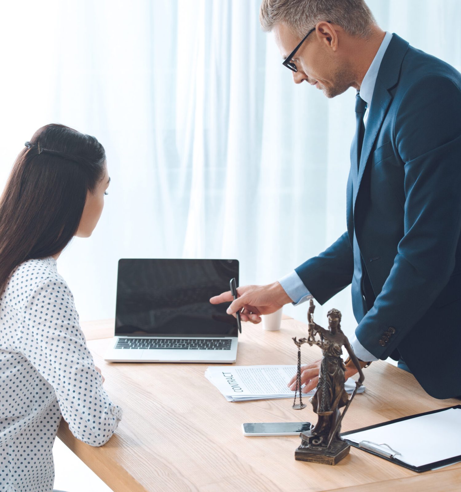 lawyer working with young female client and pointing at laptop