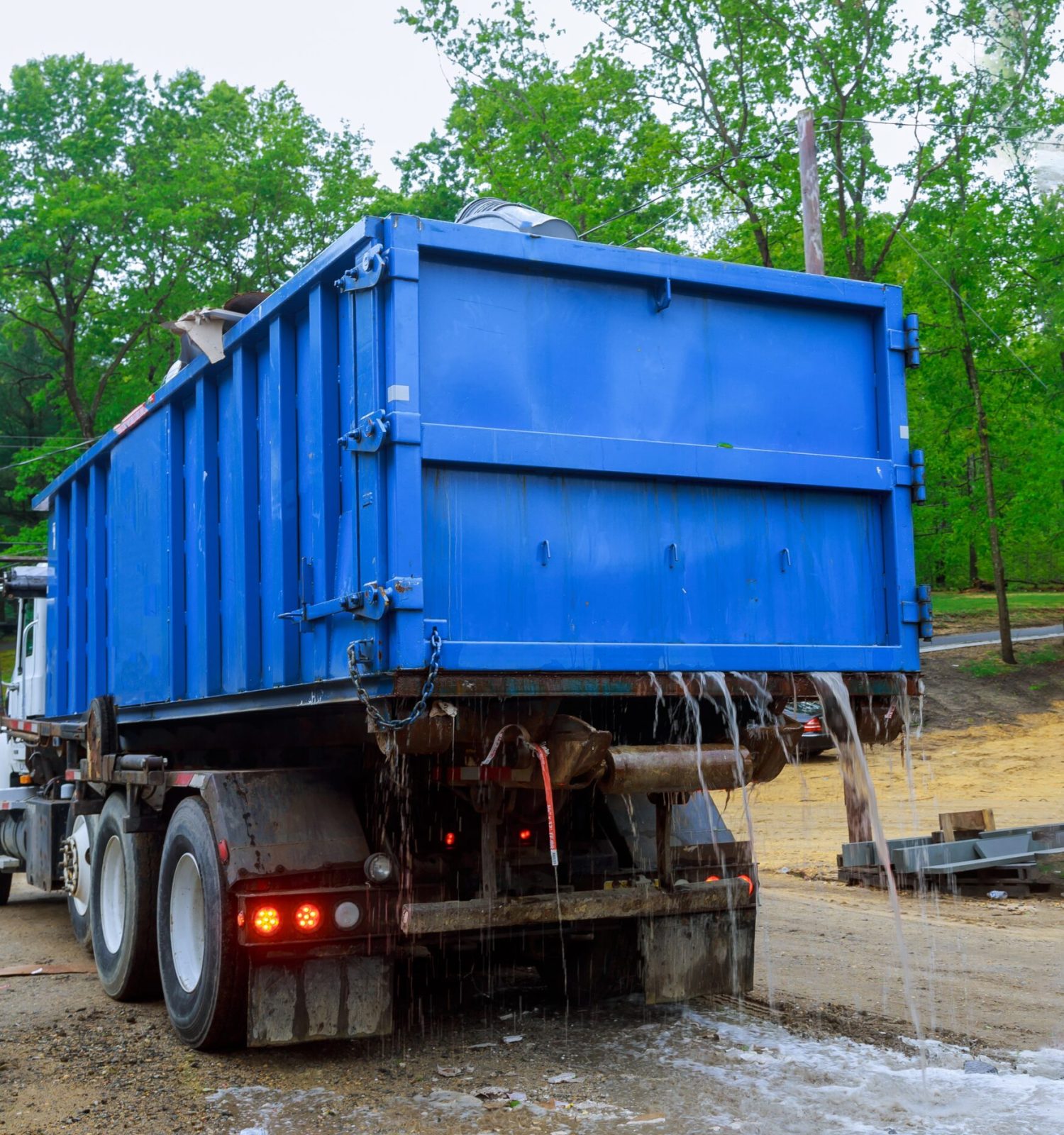 Loaded dumpster near a litterless metal container without a cover is full of construction debris waste standing in the building under construction