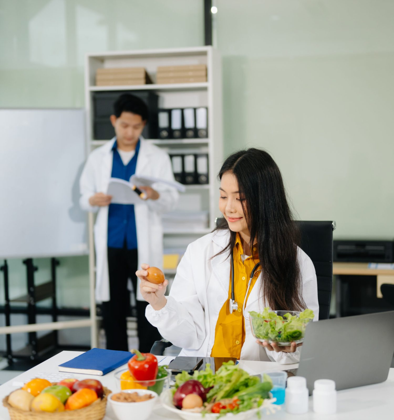 Professional nutritionist reviewing fresh vegetables and supplements for diet planning, health care, and wellness in a clinical nutrition setting